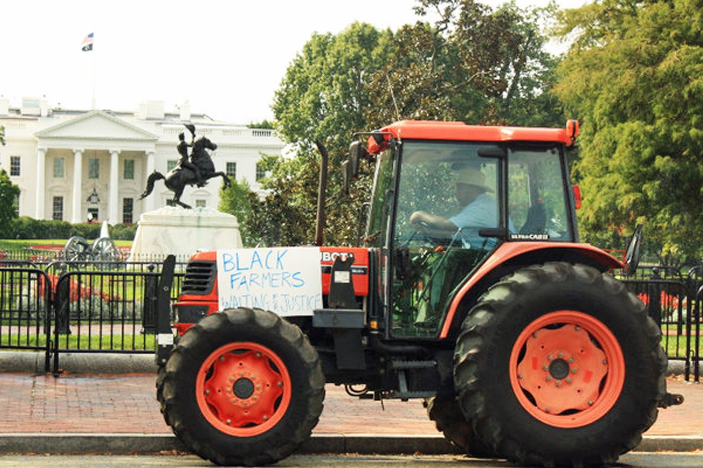 The tractor Justice parked in front of the White House with a hand-lettered sign reading Black Farmers Waiting for Justice